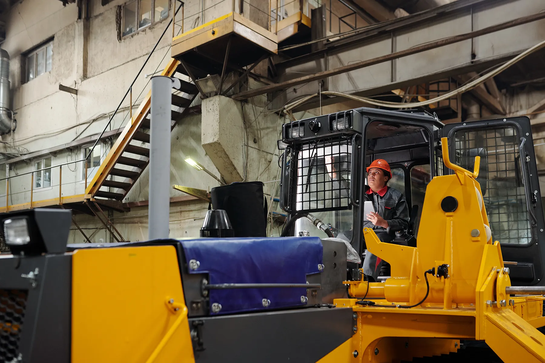 young-contemporary-female-worker-operating-constru-2025-03-13-07-33-11-utc Young contemporary female worker in workwear and safety helmet operating huge construction machine during work