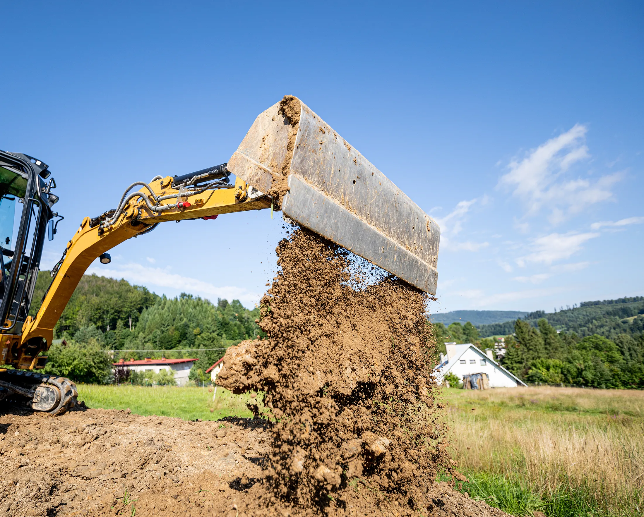 xcavator placing and compacting soil during ground improvement, illustrating how deep dynamic compaction strengthens weak soils for stable foundations.